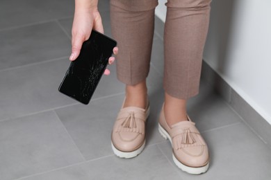 Photo of Woman with damaged smartphone indoors, closeup. Device repairing