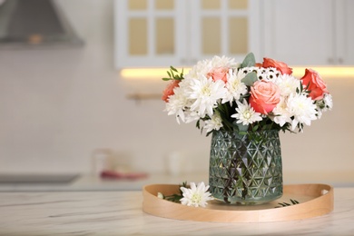 Photo of Vase with beautiful flowers on table in kitchen, space for text. Interior design