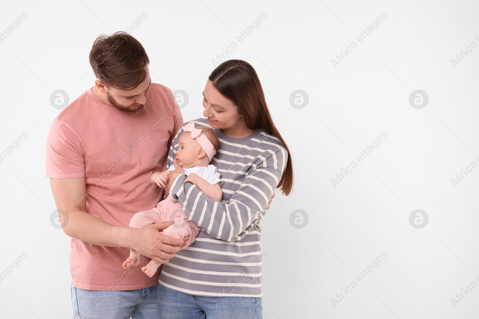 Photo of Happy family. Parents with their cute baby on light background, space for text