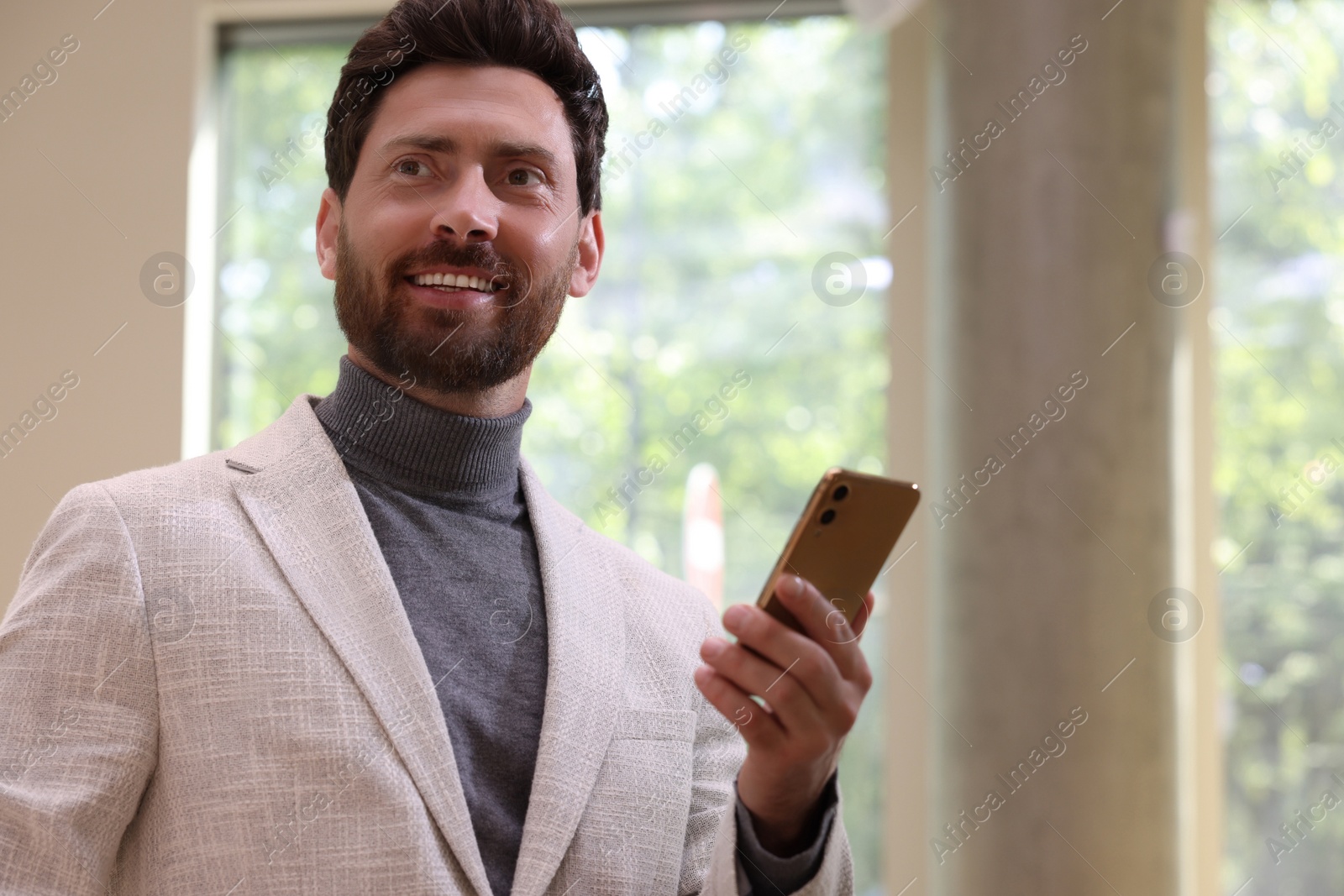 Photo of Happy handsome man with smartphone in office