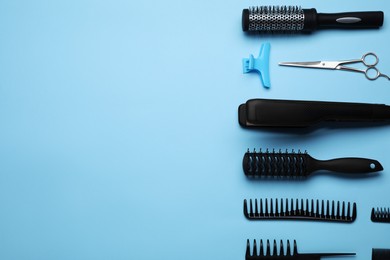 Flat lay composition of professional hairdresser tools on light blue background, space for text