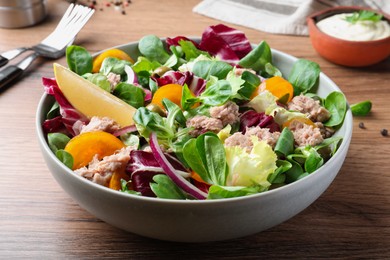 Photo of Bowl of delicious salad with canned tuna and vegetables on wooden table