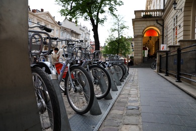 Photo of LVIV, UKRAINE - APRIL 27, 2019: Parking with bicycles for rent on Market Square near Town Hall