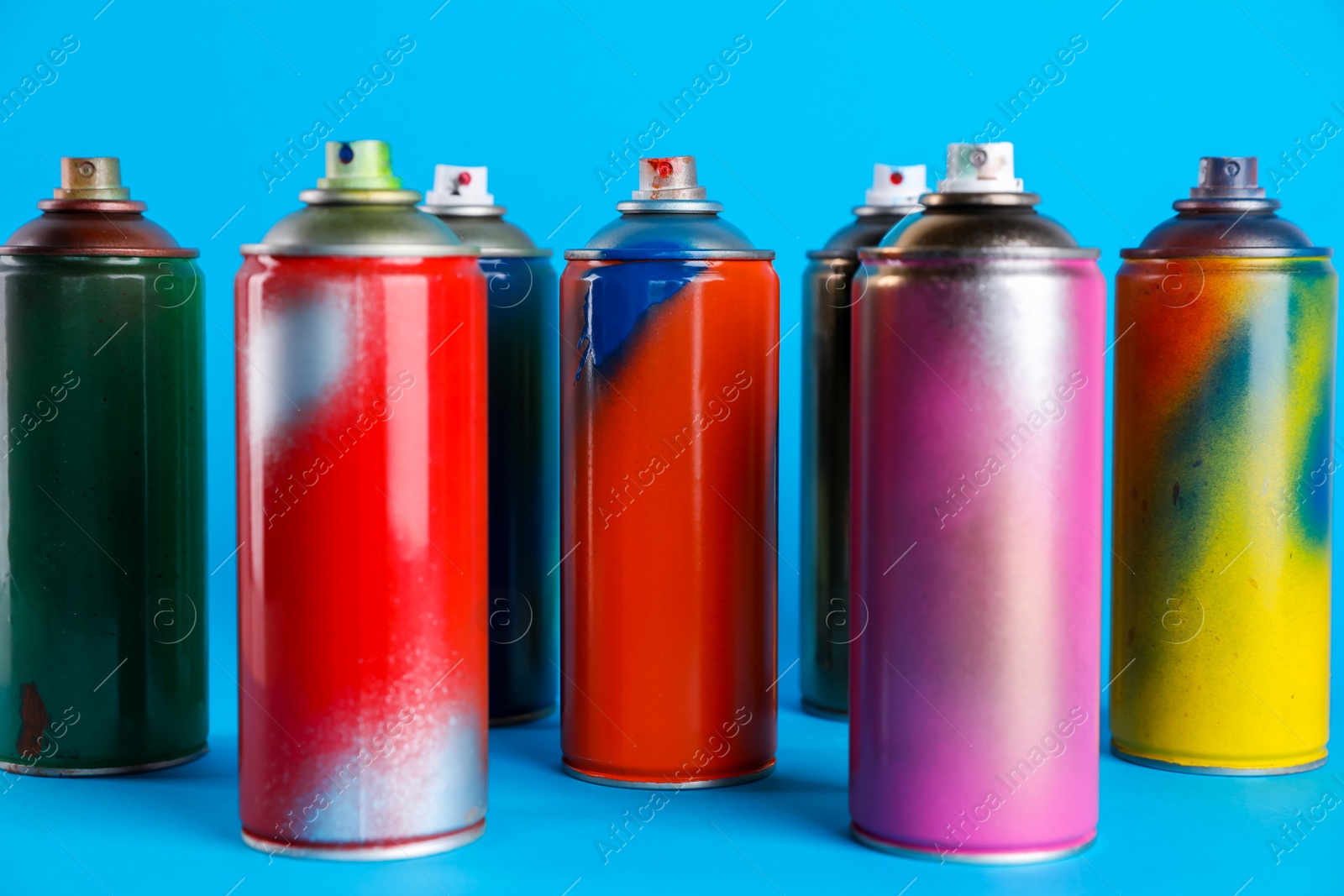 Photo of Used cans of spray paints on light blue background