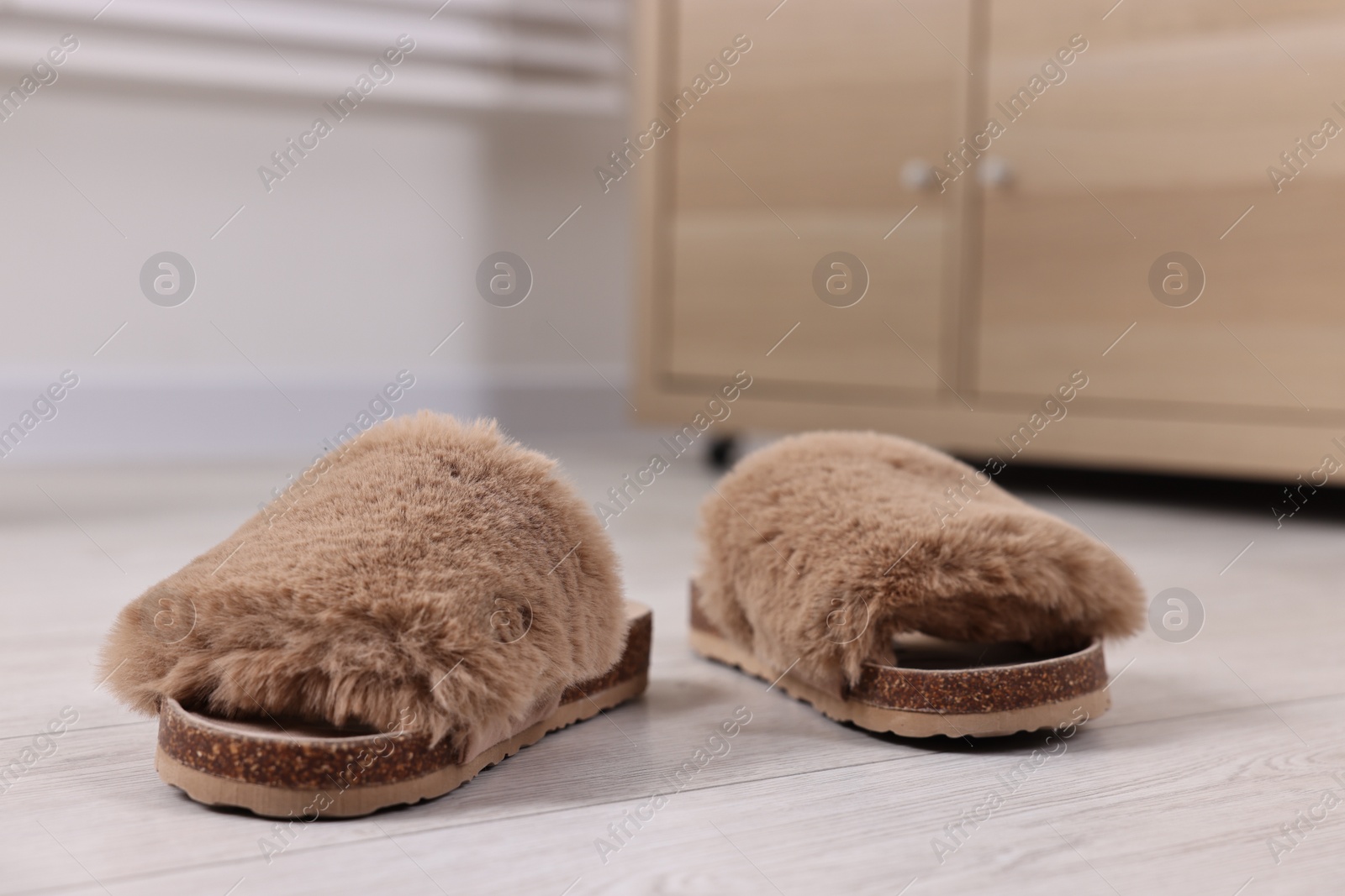 Photo of Soft slippers on light wooden floor indoors, closeup