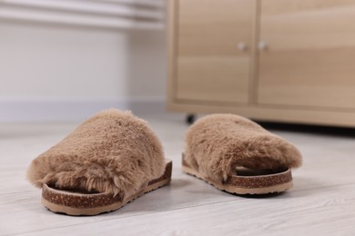Photo of Soft slippers on light wooden floor indoors, closeup