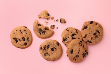 Photo of Many delicious chocolate chip cookies on pale pink background, flat lay