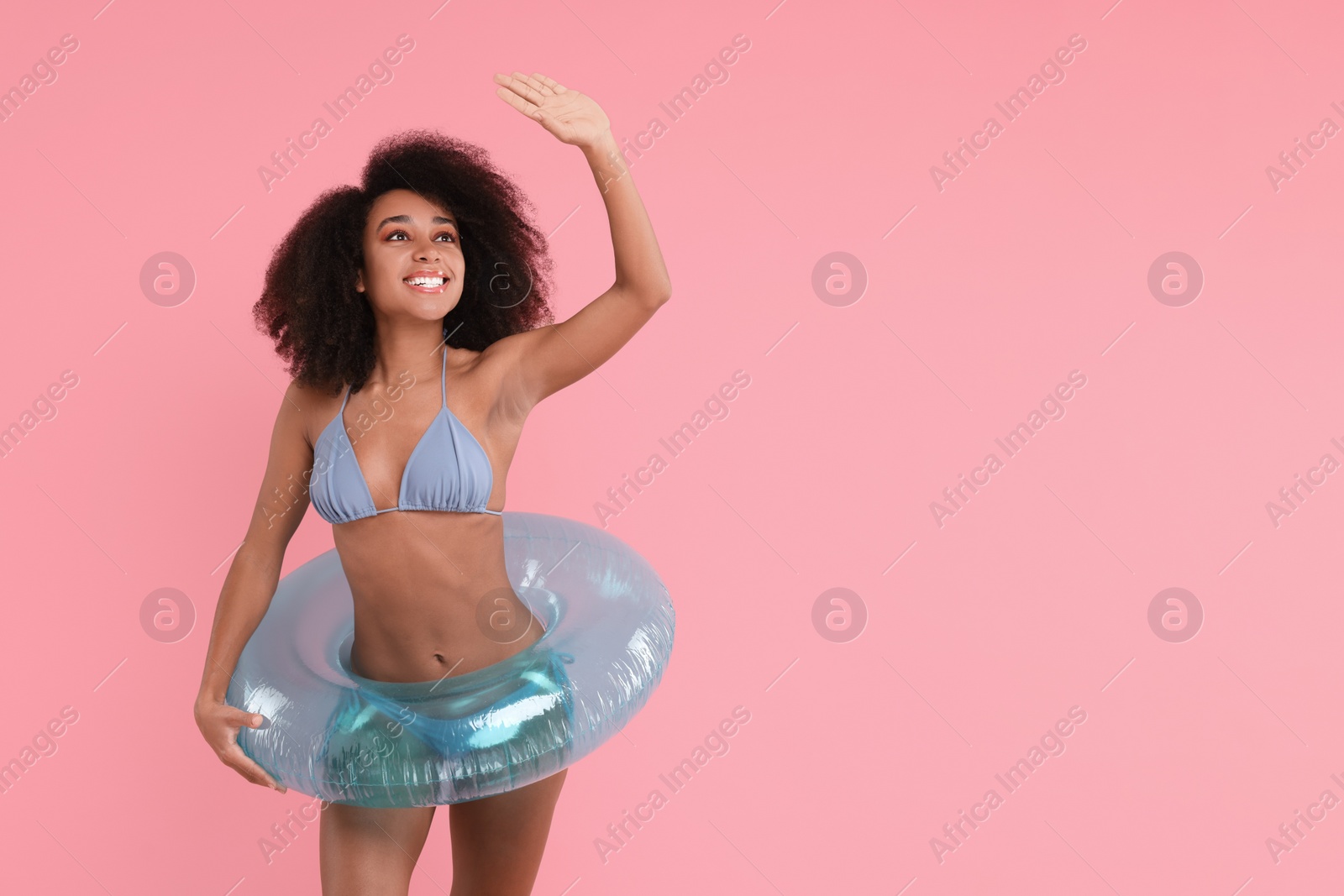 Photo of Beautiful woman in stylish bikini with inflatable ring on pink background, space for text