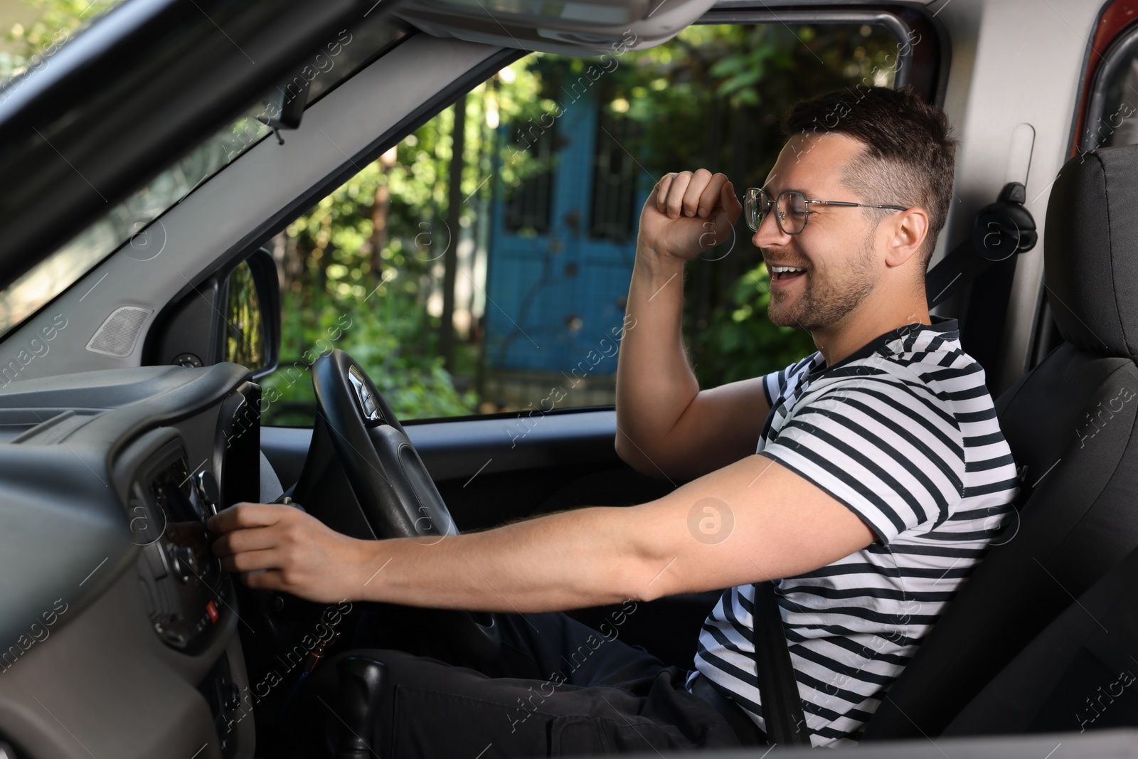 Photo of Listening to radio while driving. Handsome man turning volume button on vehicle audio in car