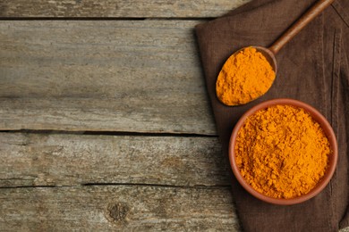 Photo of Bowl and spoon with saffron powder on wooden table, top view. Space for text