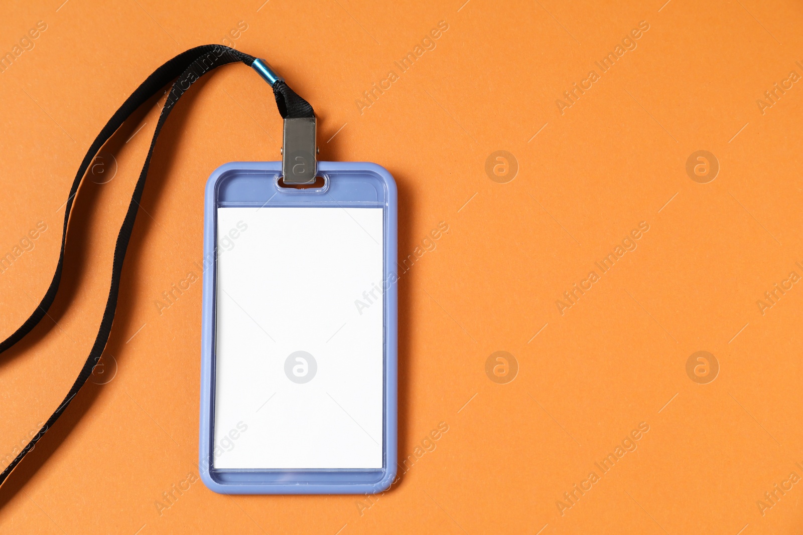 Photo of Blank badge with string on orange background, top view. Space for text