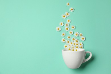 Photo of Flat lay composition with beautiful daisy flowers and ceramic cup on turquoise background. Space for text