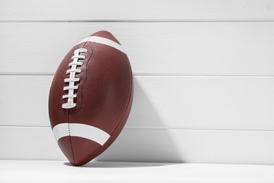 Photo of American football ball on white wooden background, space for text
