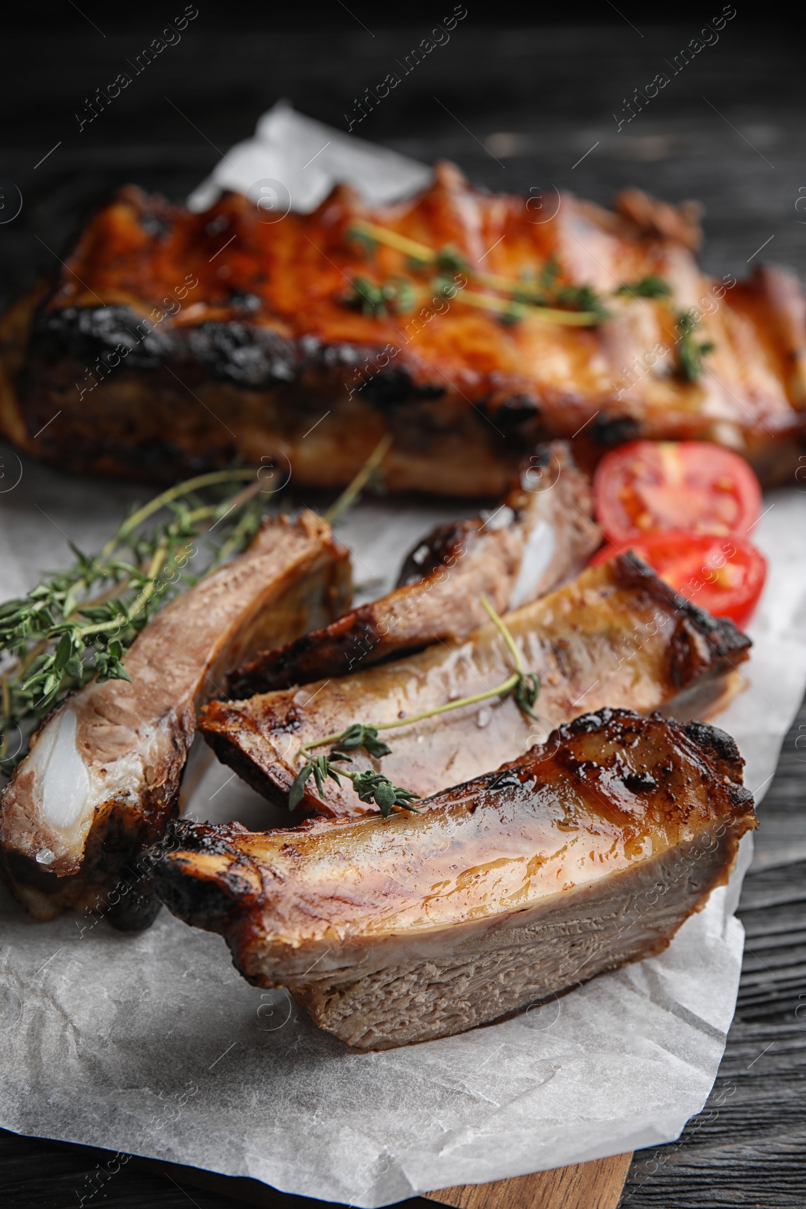 Photo of Tasty grilled ribs on black wooden table, closeup