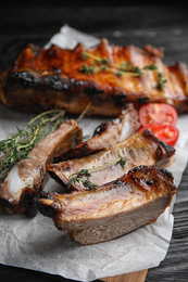 Photo of Tasty grilled ribs on black wooden table, closeup