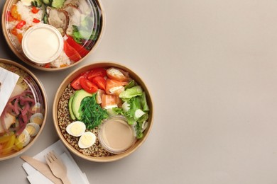 Photo of Tasty food in containers with wooden knife and fork on light grey table, flat lay. Space for text