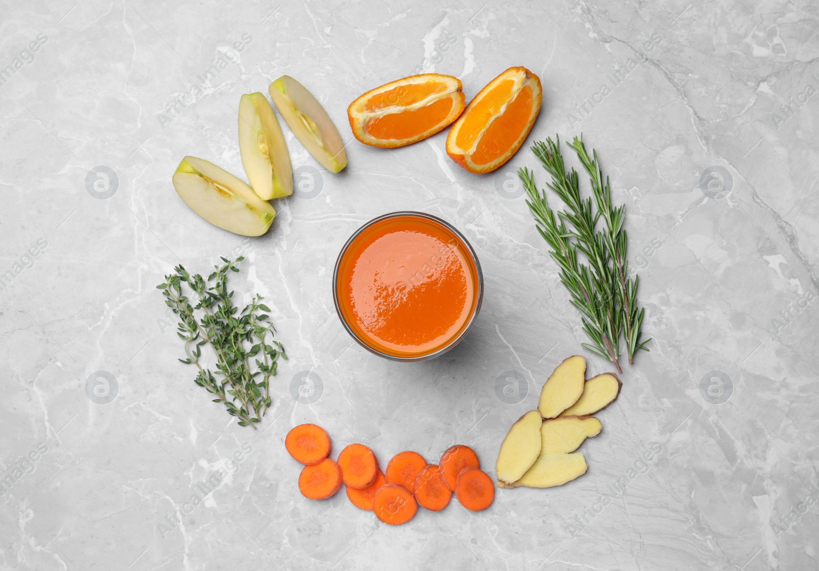 Photo of Flat lay composition with healthy carrot juice in glass and ingredients on grey marble table