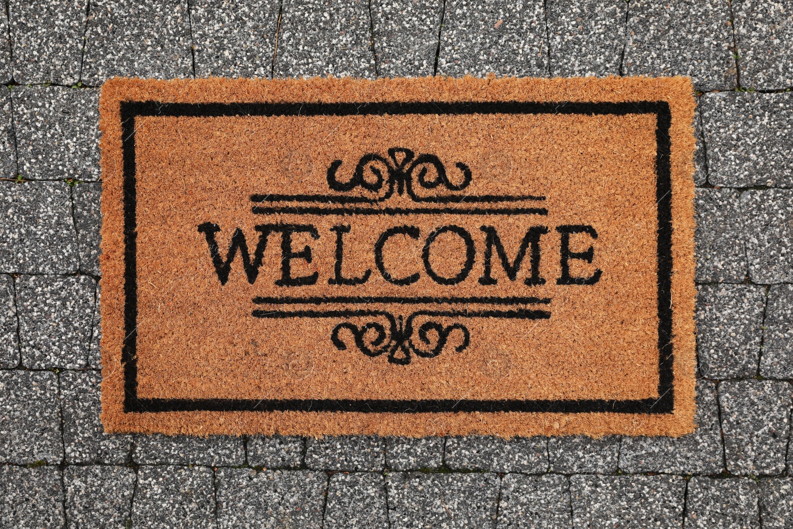 Photo of Doormat with word Welcome on pavement outdoors, top view