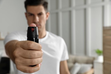 Photo of Man using pepper spray at home, focus on hand. Space for text