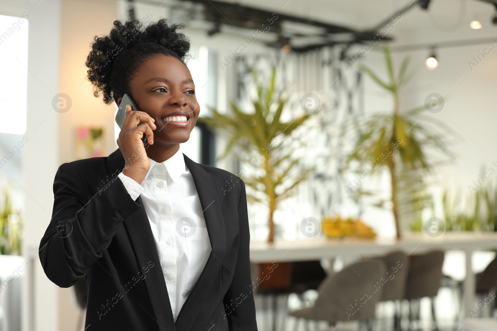 Photo of Happy woman talking on smartphone in office, space for text. Lawyer, businesswoman, accountant or manager