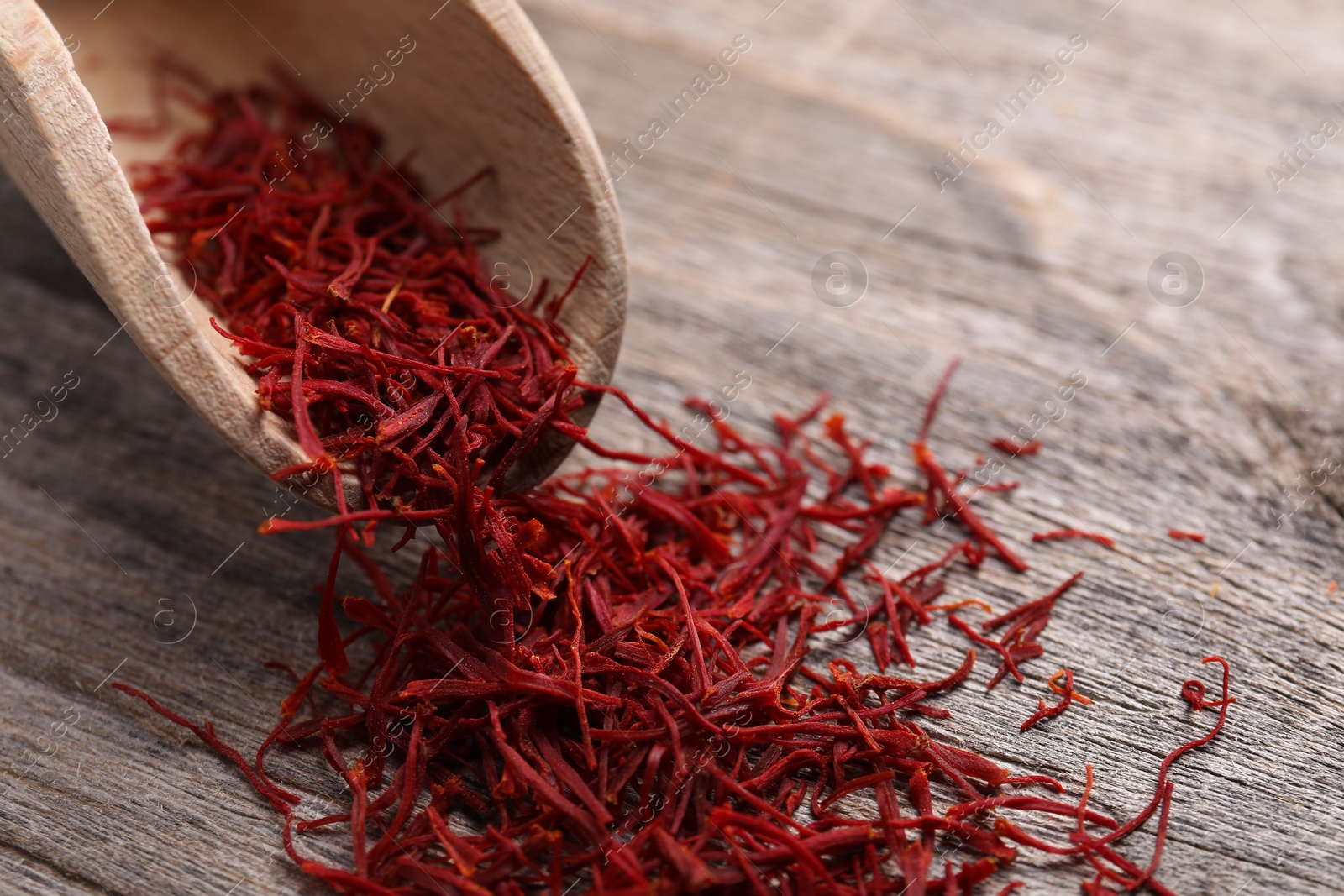 Photo of Aromatic saffron and scoop on wooden table, closeup