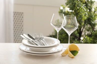 Photo of Set of clean dinnerware and lemon on table indoors