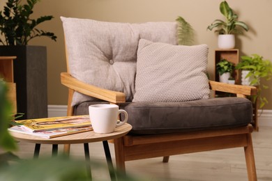 Photo of Comfortable armchair near wooden coffee table in room. Interior design