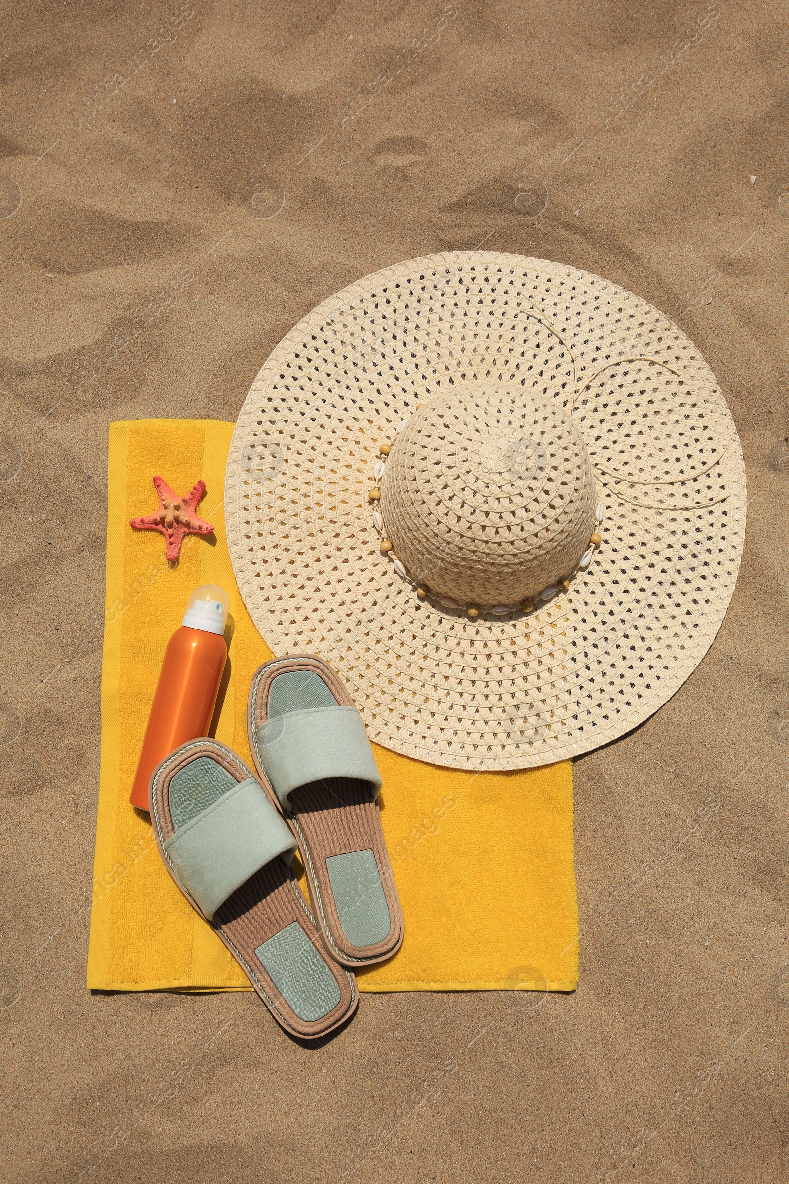 Photo of Sunscreen, starfish and beach accessories on sand, top view. Sun protection care