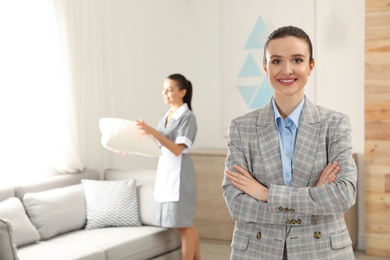 Photo of Portrait of housekeeping manager and blurred maid in hotel room. Space for text