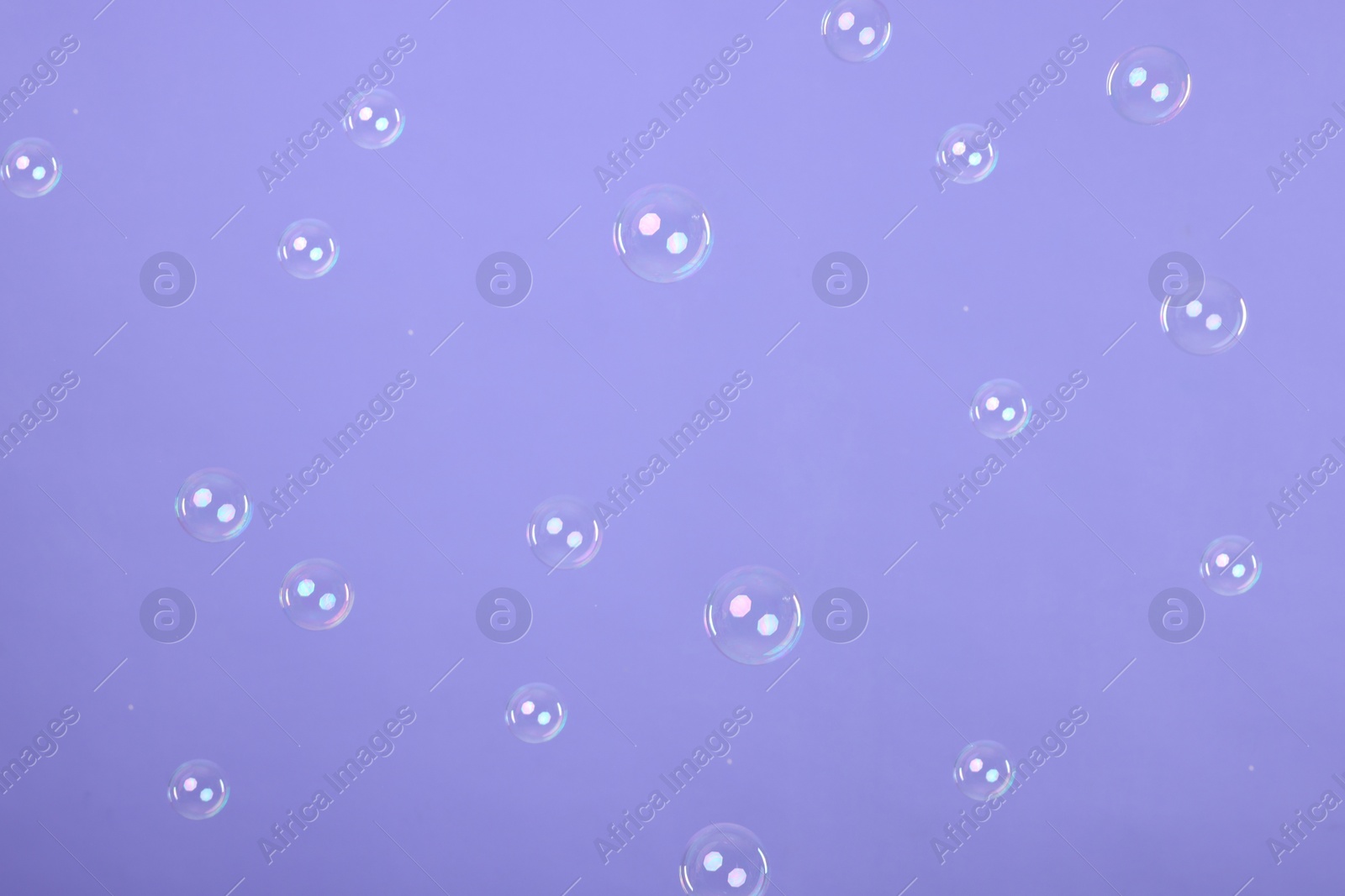 Photo of Many beautiful soap bubbles on violet background