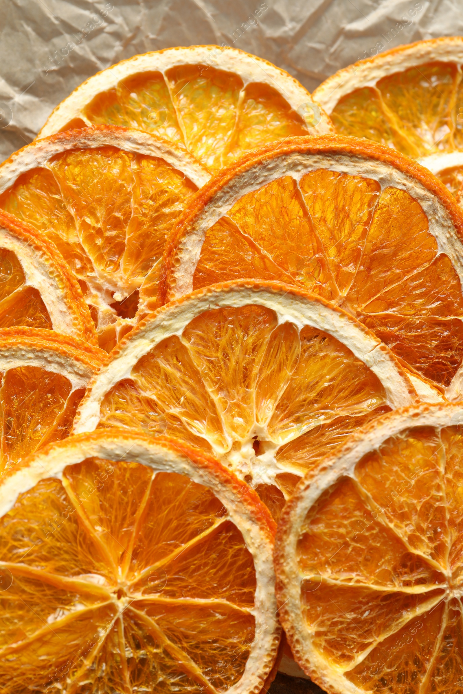Photo of Many dry orange slices on parchment paper, closeup