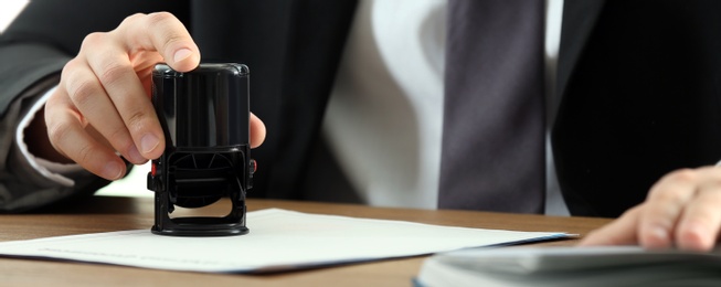 Image of Notary stamping document at table, closeup. Banner design