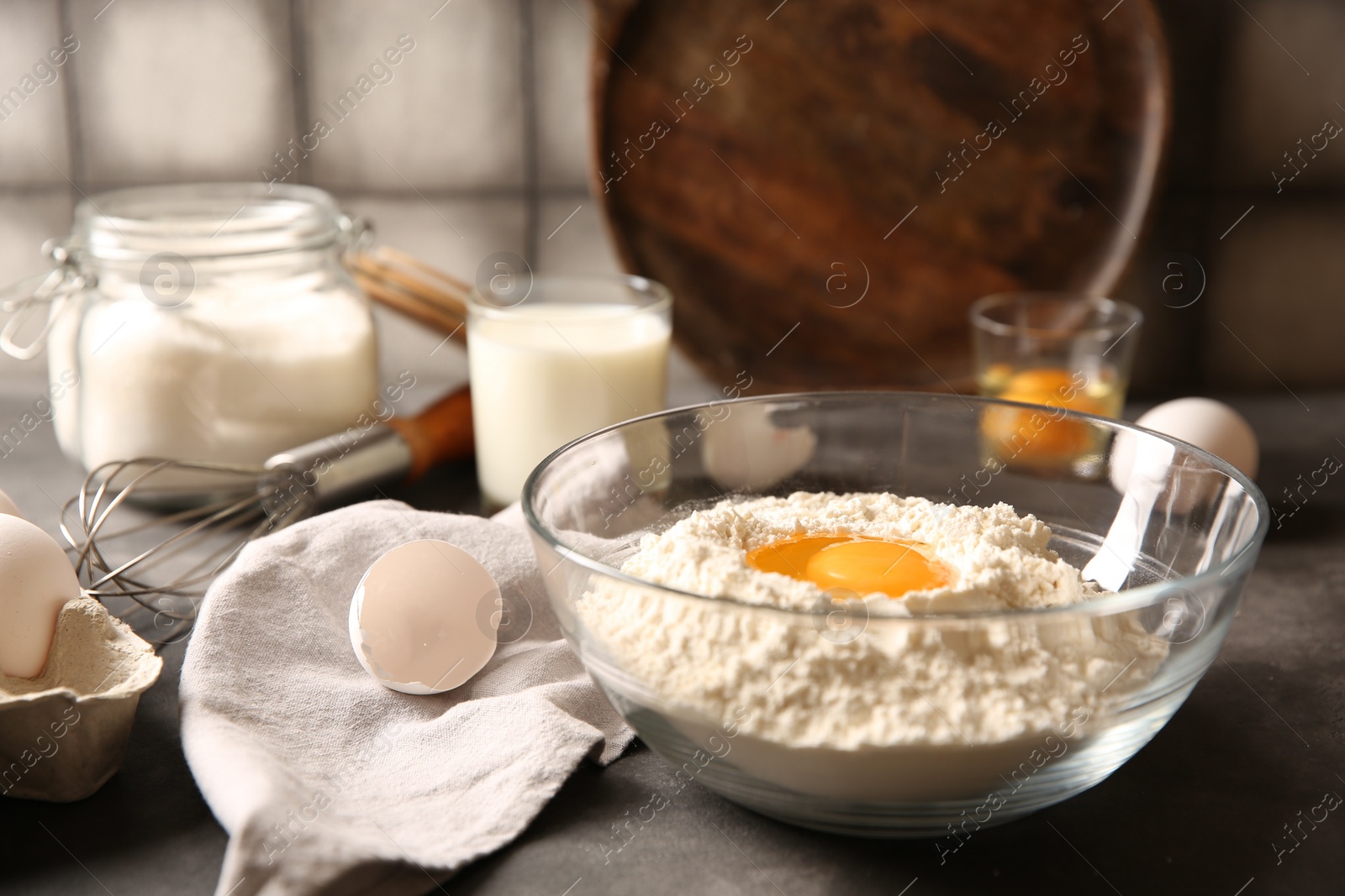 Photo of Making dough. Flour with egg yolk in bowl on grey table, closeup