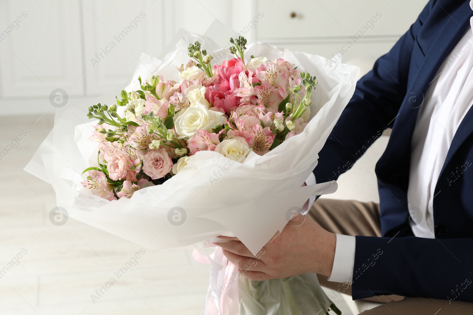 Photo of Man with beautiful bouquet of flowers indoors, closeup