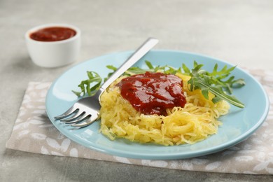 Photo of Tasty spaghetti squash with tomato sauce and arugula served on light grey table