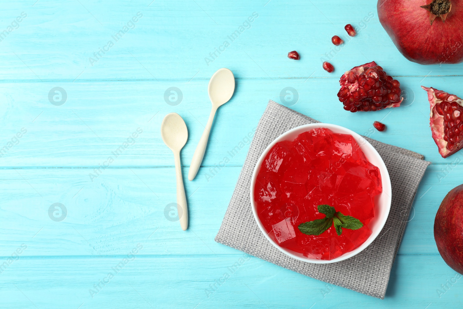 Photo of Flat lay composition with red jelly in bowl and pomegranate on wooden background. Space for text