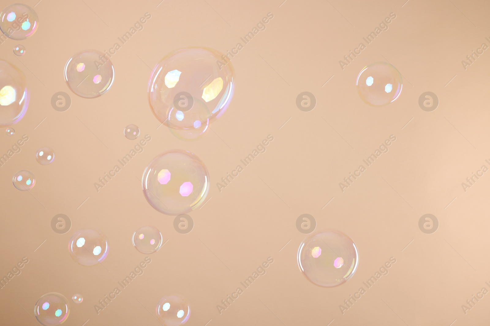 Photo of Many beautiful soap bubbles on beige background