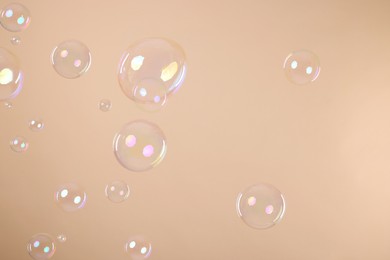 Photo of Many beautiful soap bubbles on beige background