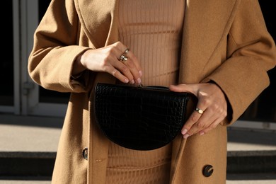 Photo of Young woman with stylish waist bag outdoors, closeup