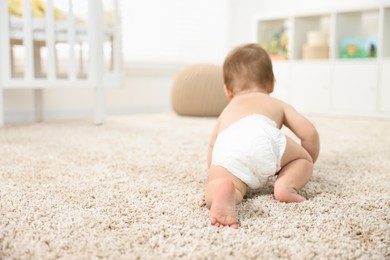 Photo of Baby boy crawling on carpet at home, back view. Space for text