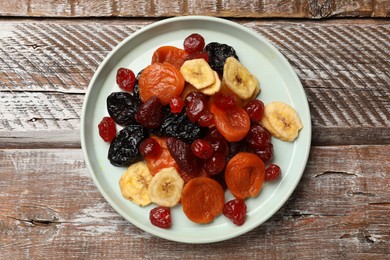 Photo of Mix of delicious dried fruits on wooden table, top view