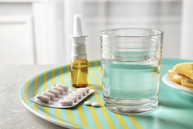 Photo of Glass with water and different cold remedies on tray