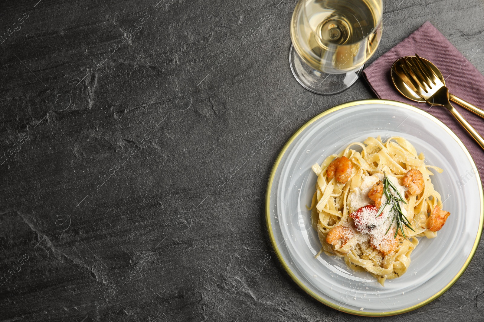 Photo of Delicious pasta with shrimps served on black table, flat lay. Space for text