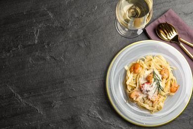 Delicious pasta with shrimps served on black table, flat lay. Space for text