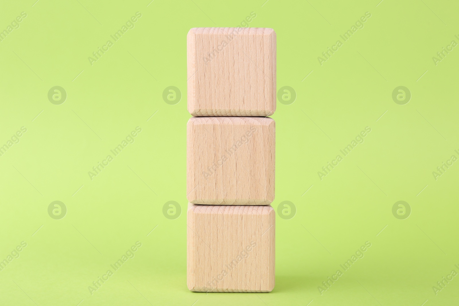 Photo of Stack of empty wooden cubes on light green background