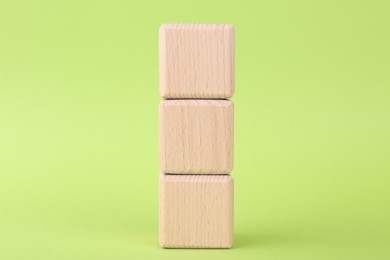 Stack of empty wooden cubes on light green background