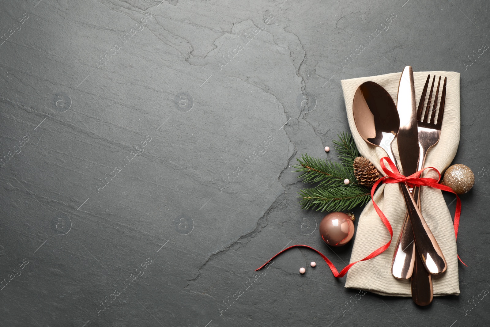 Photo of Cutlery set and festive decor on black slate table, flat lay with space for text. Christmas celebration