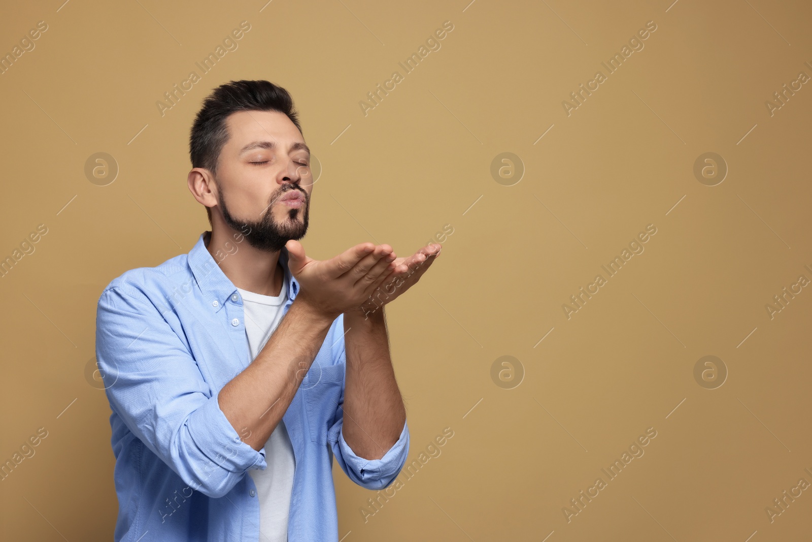 Photo of Handsome man blowing kiss on beige background. Space for text