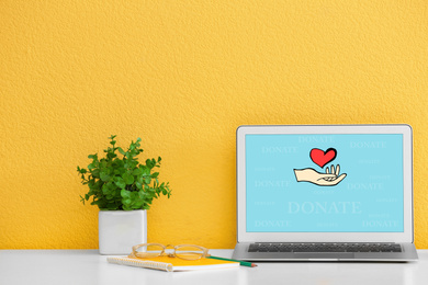 Image of Donations concept. Modern laptop on table near yellow wall