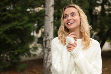 Happy woman in stylish warm sweater outdoors. Space for text